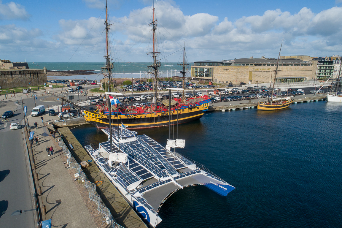 Le catamaran dans le port de Saint-Malo. En arrière plan, son vénérable ancêtre le navire "L'ETOILE DU ROY".