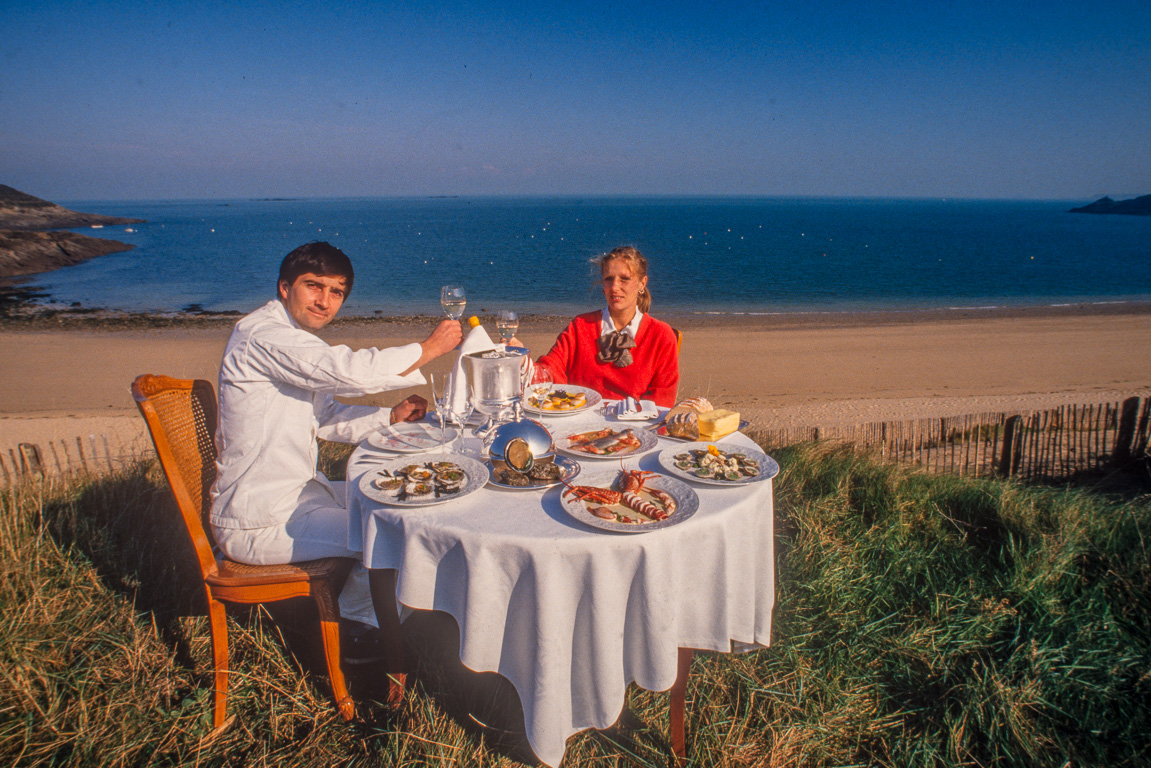 Cancale 1994. Avec sa femme autour d'une table richement garnie, installée sur les dunes dominant la mer, pour les besoins d'une photo destinée  au magazine VSD.