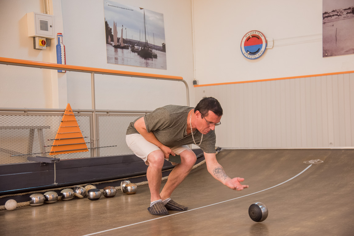 Bouchemaine, la Pointe. La Bonne Alliance association du jeu de la Boule de Fort. Le "rouleur" se baisse au maximum pour ne pas laisser tomber sa boule et l'envoie lentement, en l'accompagnant.