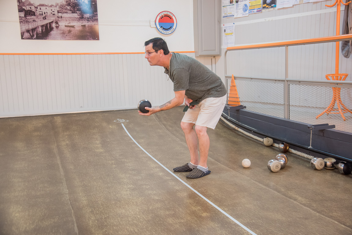 Bouchemaine, la Pointe. La Bonne Alliance association du jeu de la Boule de Fort. Le "rouleur" se baisse au maximum pour ne pas laisser tomber sa boule et l'envoie lentement, en l'accompagnant.