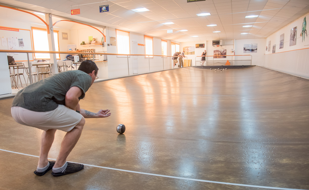 Bouchemaine, la Pointe. La Bonne Alliance association du jeu de la Boule de Fort. Le "rouleur" se baisse au maximum pour ne pas laisser tomber sa boule et l'envoie lentement, en l'accompagnant.