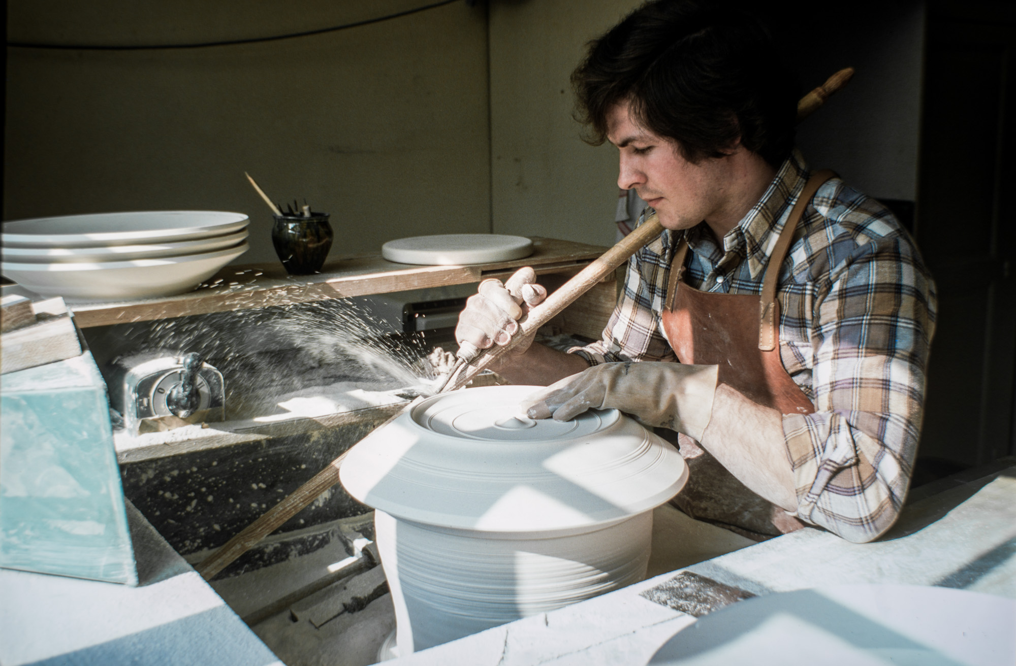 Tournassage d'une assiette à l'aide d'un trusquin sur la porcelaine sèche et non cuite.