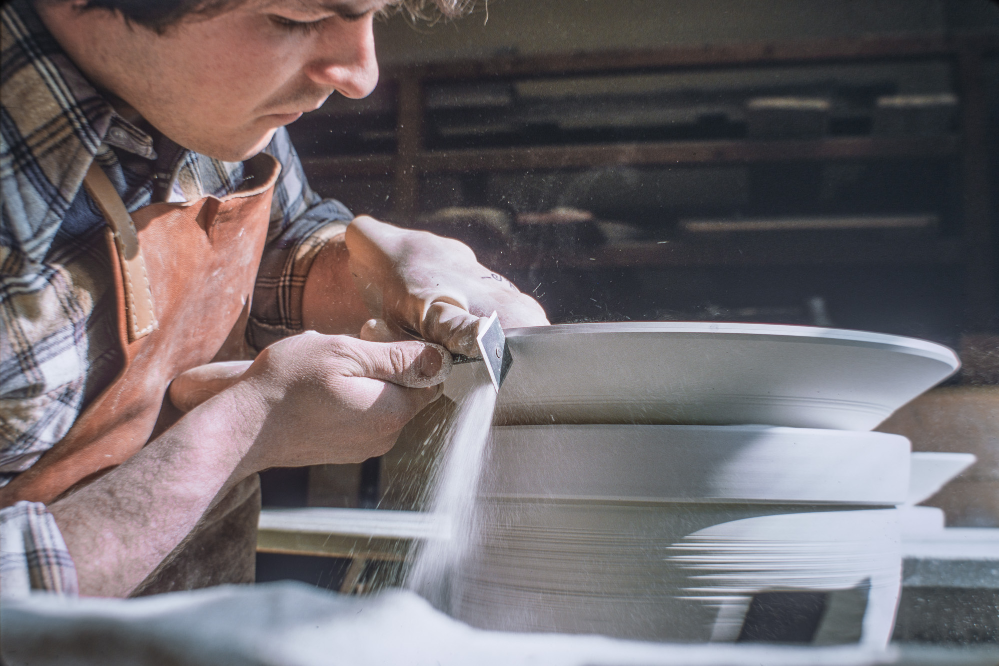 Tournassage d'une assiette à l'aide d'un trusquin sur la porcelaine sèche et non cuite.