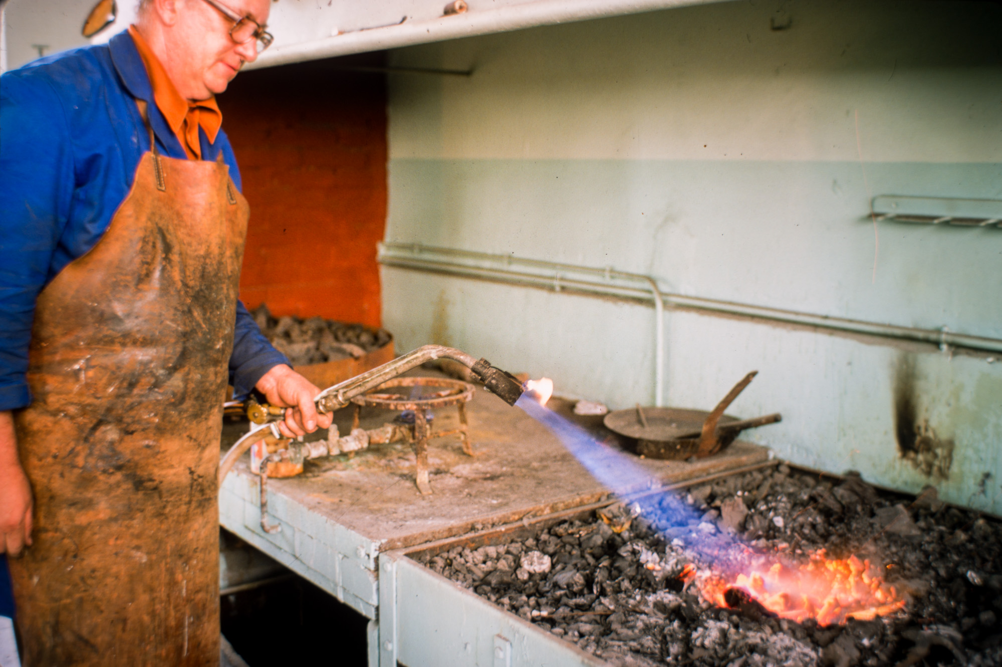 Chaudronnier en bronze travaille une pièce sous la châleur de la forge..