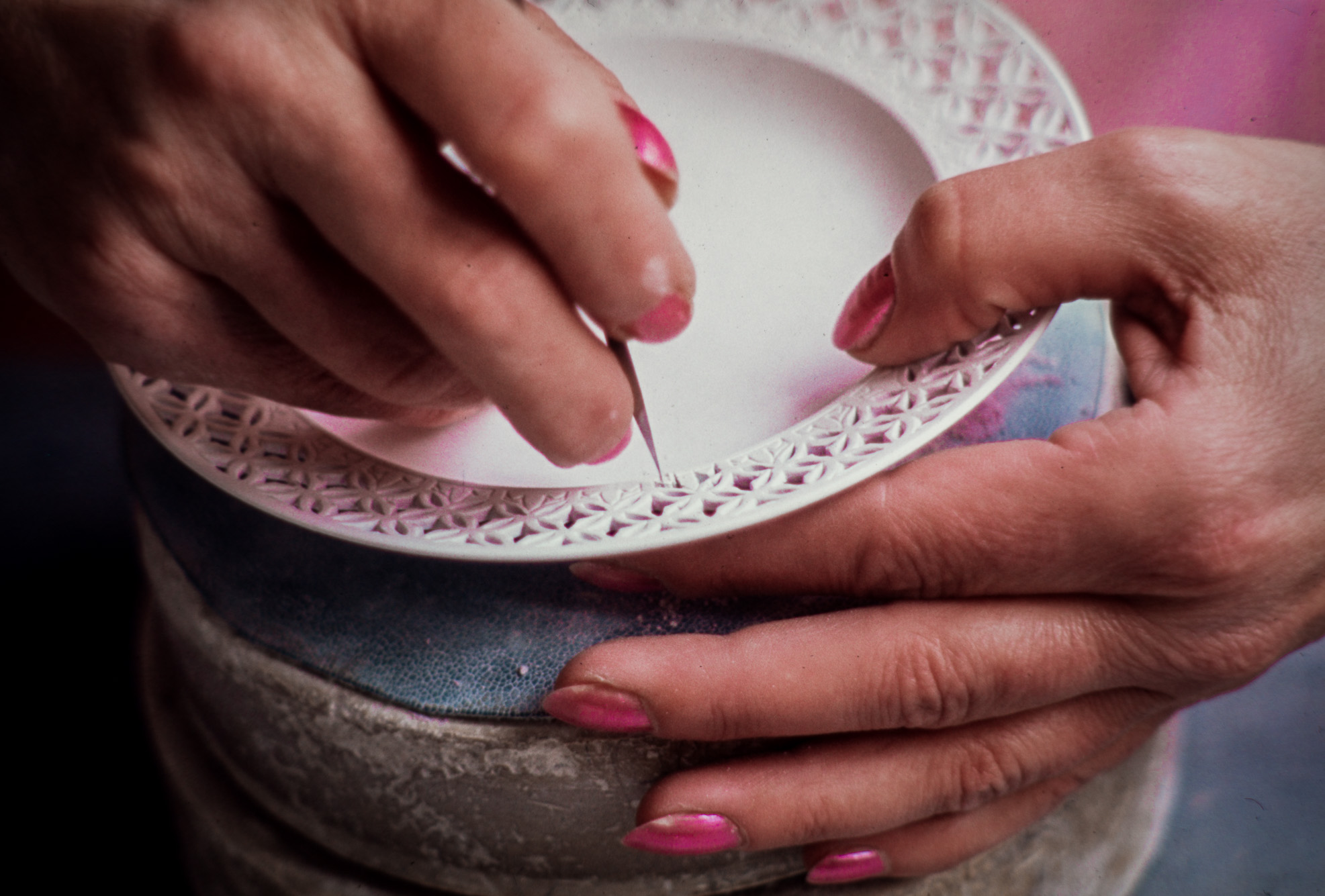 Atelier du garnissage découpage. L'ajour de cette tasse en "réticulé chinois" est réalisé à l'aide de minuscules outils sur la porcelaine sèche et non cuite.